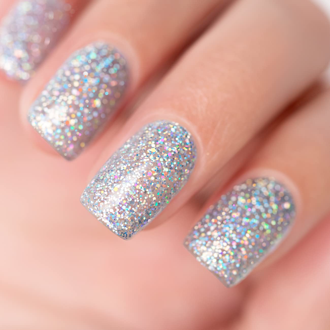 Cosmic silver holographic glitter manicure with ultra-dense rainbow iridescent sparkles on nails close-up
