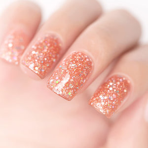 Peachy coral orange glitter manicure with iridescent holographic pink gold sparkles on nails

