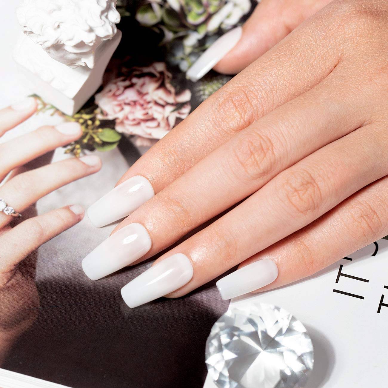 Milky white creamy opaque manicure long coffin nails natural elegant look on hand with book
