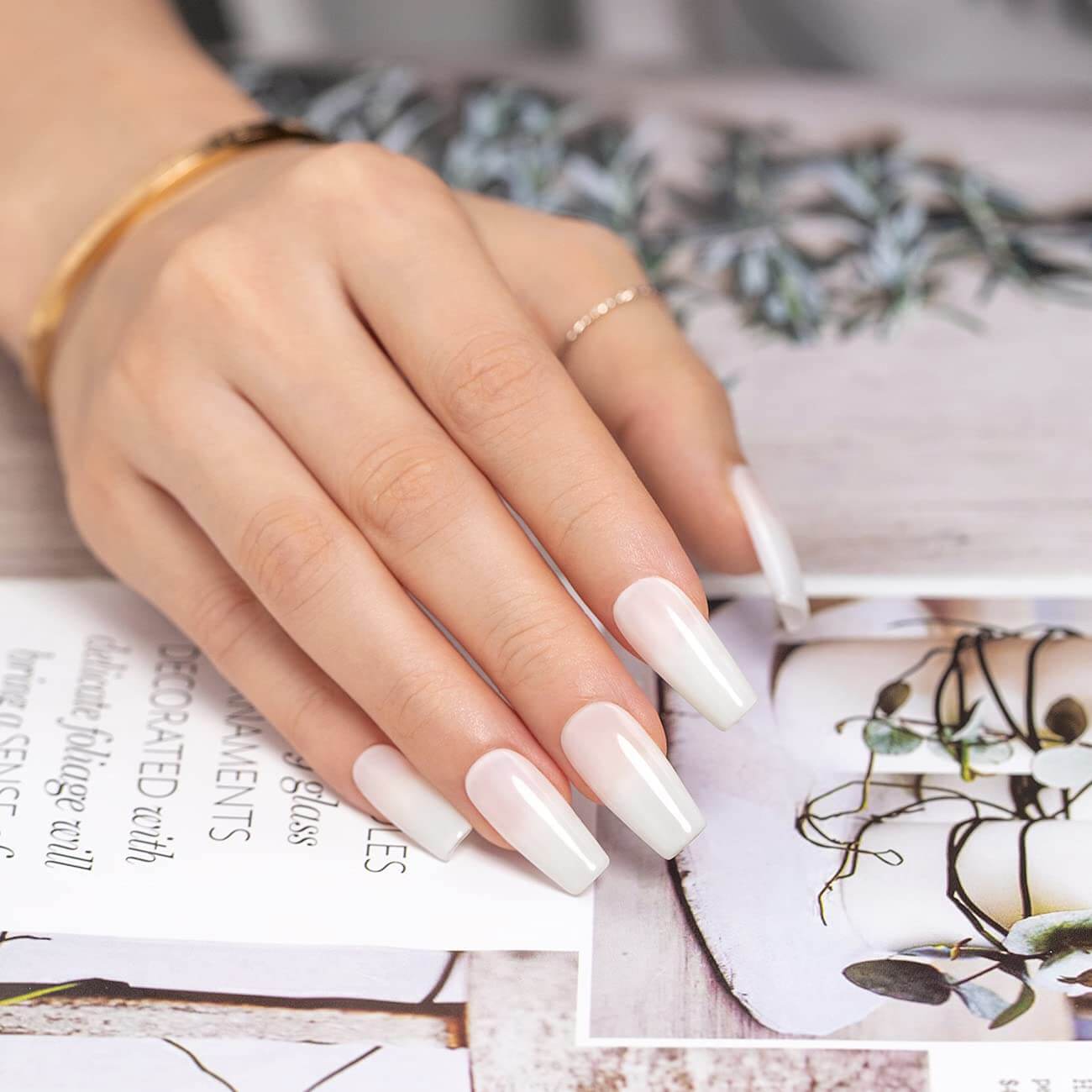 Milky white gel polish manicure close-up short square nails creamy opaque finish on hand with flowers
